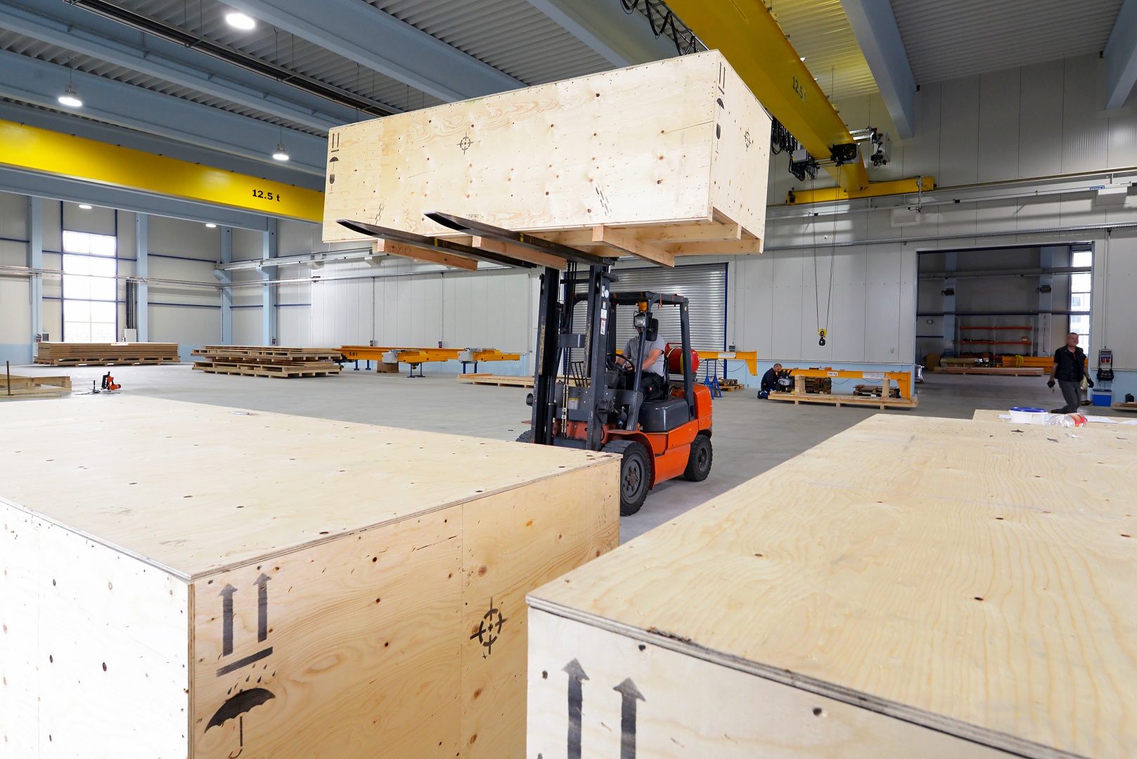 Gabelstapler bewegt große holzkiste mit Waren in einer industriehalle