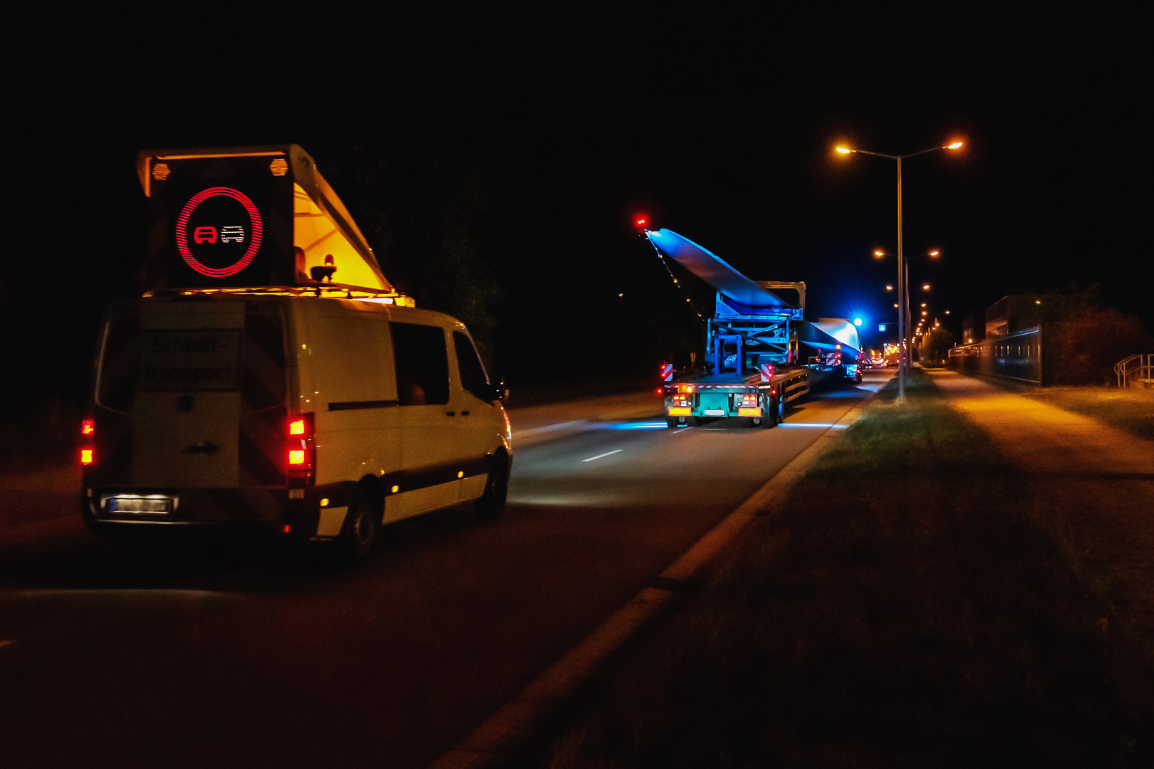 Ein Schwertransport mit Rotorblättern fährt in der Nacht auf der Straße