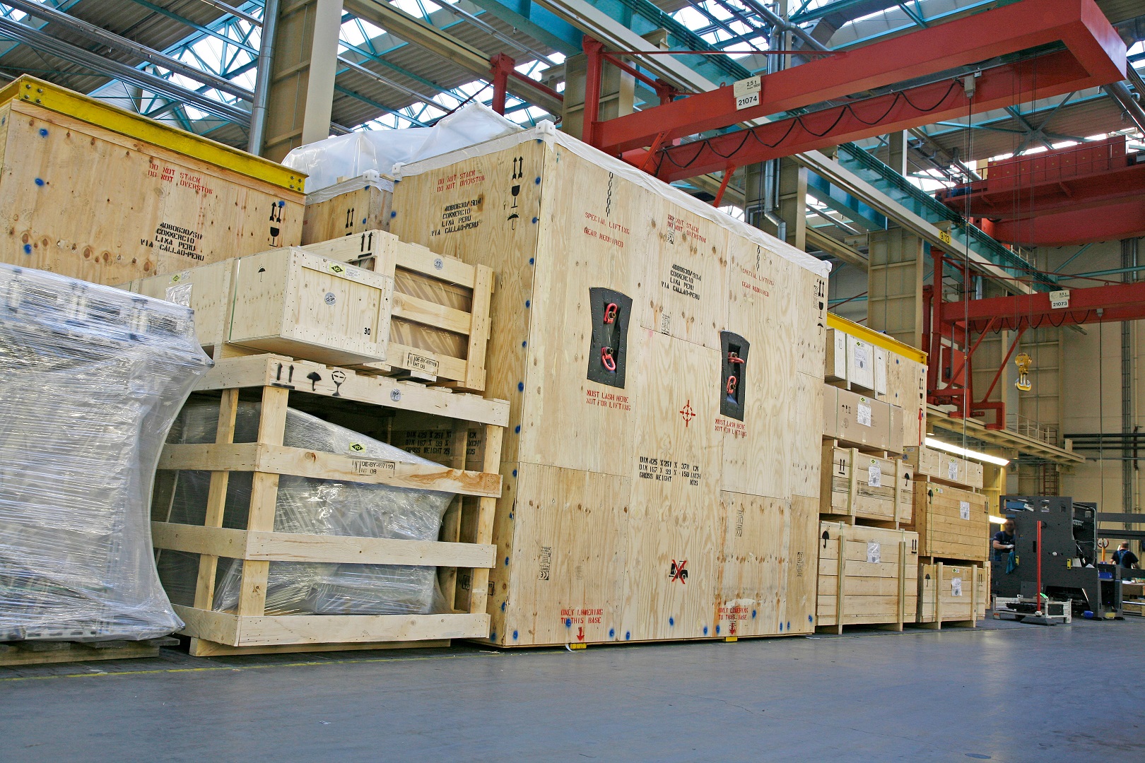 Transport crates and packaged machine parts in an industrial hall